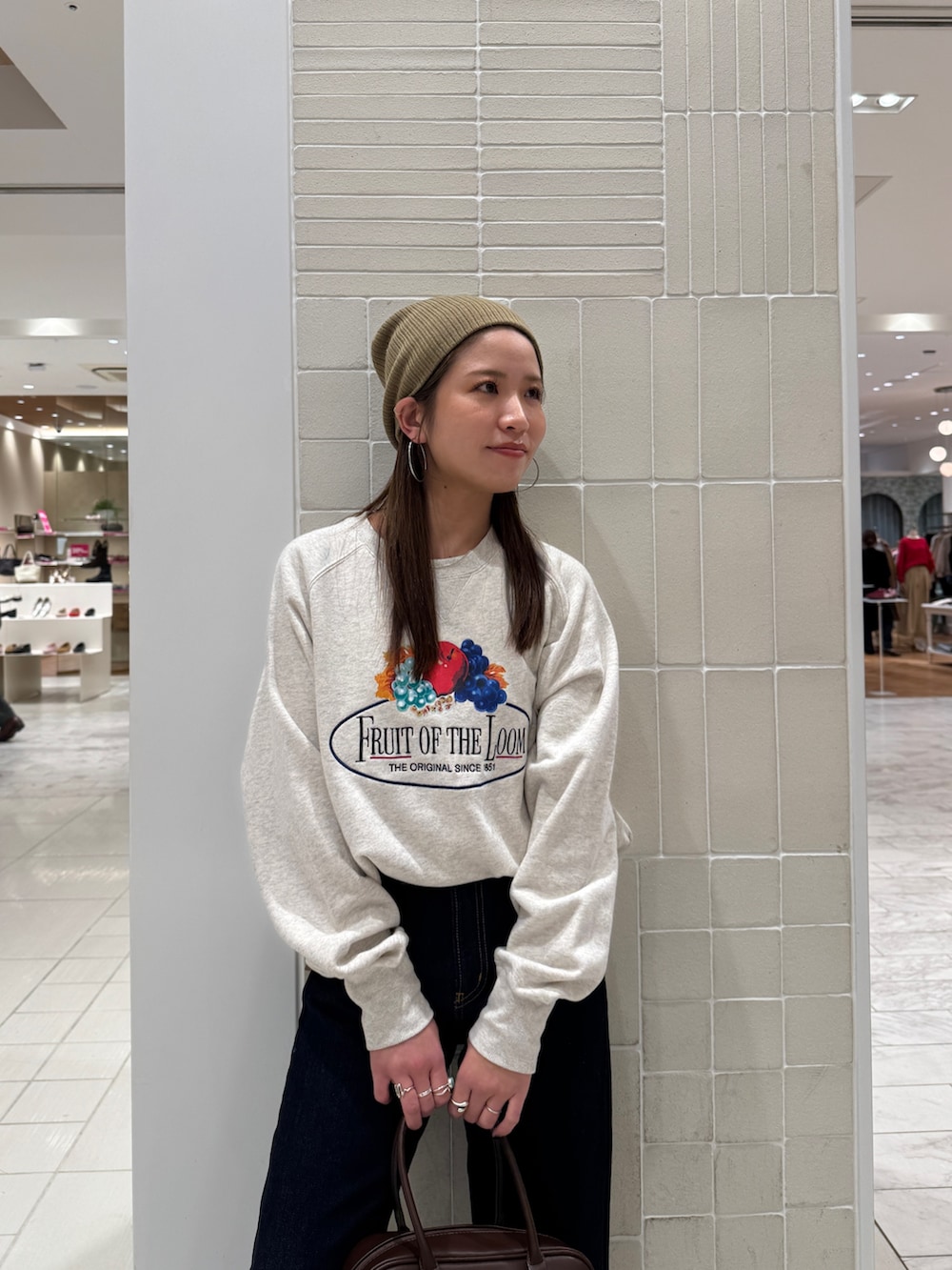 ホワイト系のスウェット、ブルー系のデニムパンツ、ブラウン系のハンドバッグを着用したレディースの冬コーディネートの7枚目の写真