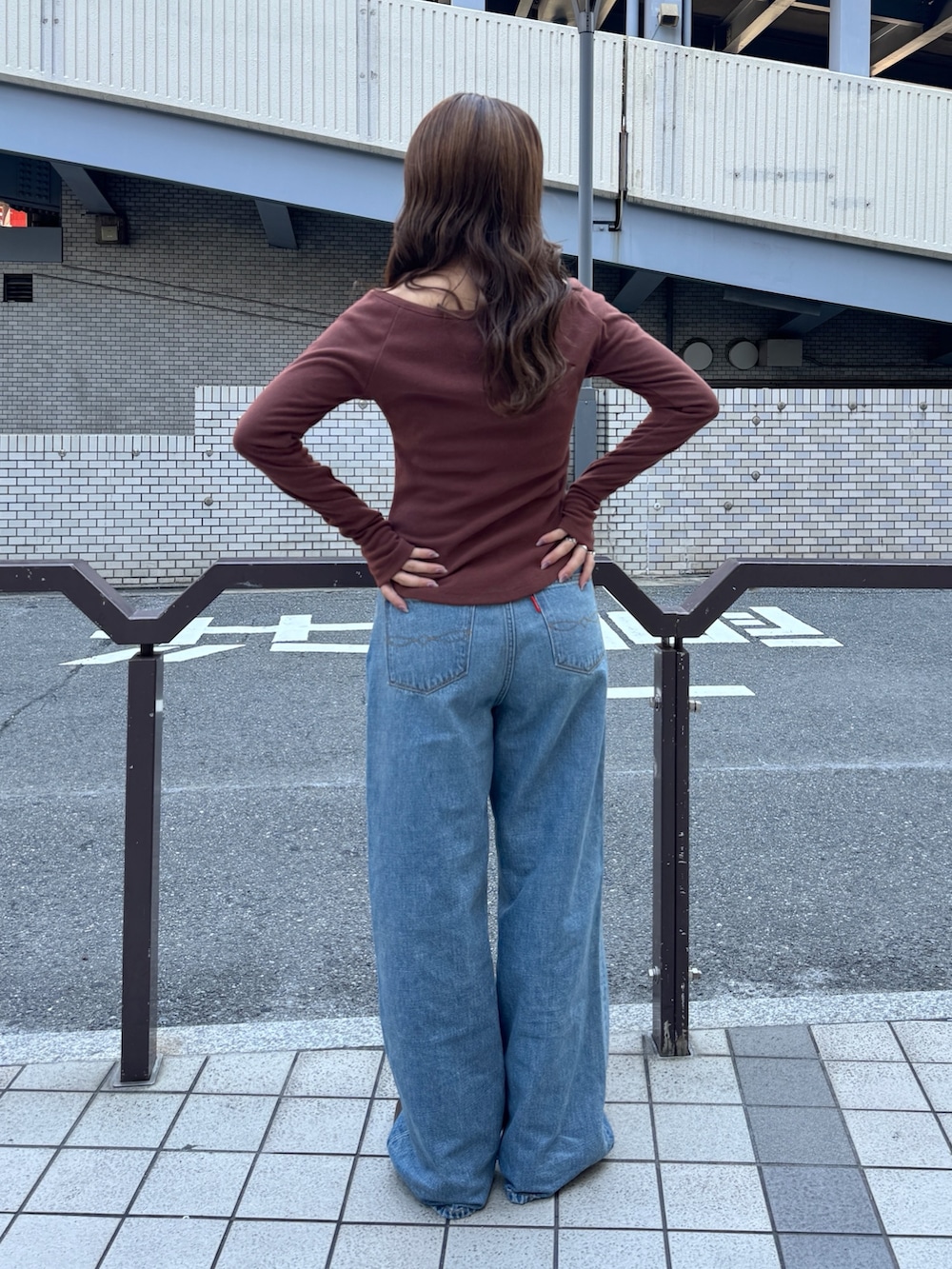 ブルー系のデニムパンツ、ブラウン系のTシャツ/カットソー、ブラウン系のブーツを着用したレディースの秋コーディネートの3枚目の写真