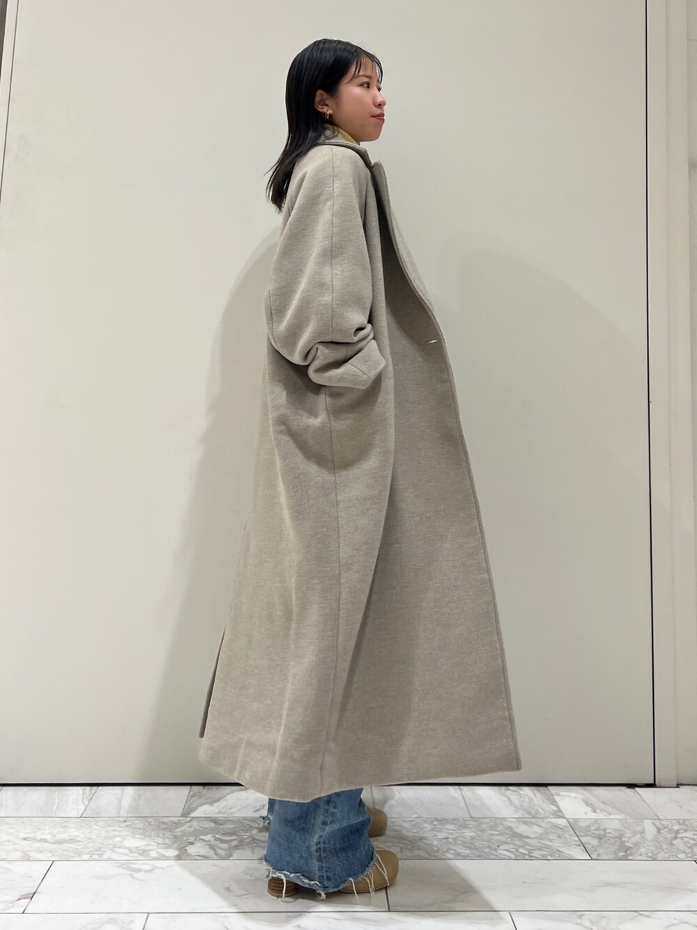 グレー系のチェスターコート、イエロー系のニット/セーター、ブルー系のデニムパンツを着用したレディースの秋コーディネートの7枚目の写真