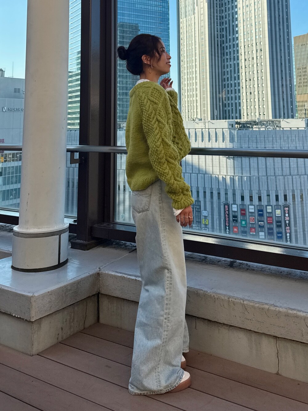 グリーン系のニット/セーター、ホワイト系のTシャツ/カットソー、ブルー系のデニムパンツを着用したレディースの冬コーディネートの5枚目の写真