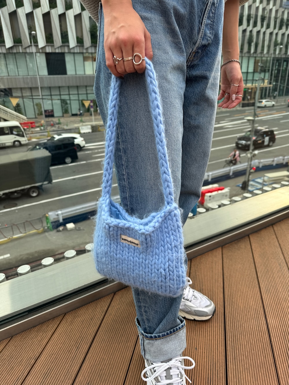 ブルー系のハンドバッグ、グレー系のニット/セーター、ブルー系のデニムパンツを着用したレディースの秋コーディネートの10枚目の写真