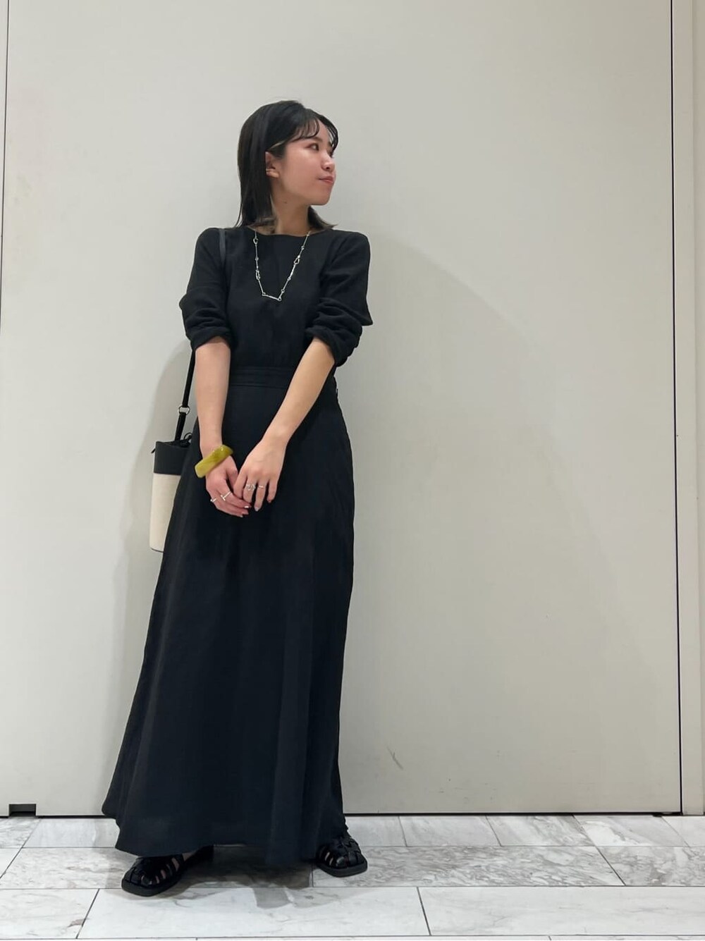 ブラック系のワンピース、ブラック系のショルダーバッグ、ブラック系のサンダルを着用したレディースの春コーディネートの2枚目の写真