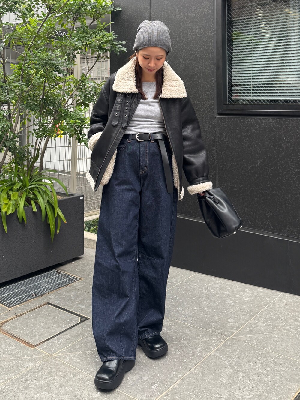 ブラック系のブルゾン、ブルー系のデニムパンツ、グレー系のニット/セーターを着用したレディースの秋コーディネートの2枚目の写真