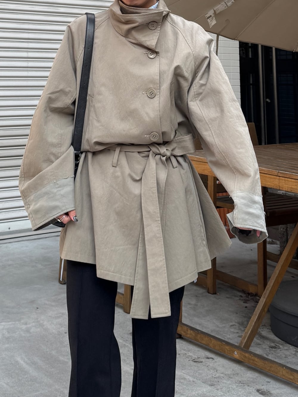 グリーン系のトレンチコート、ブラック系のその他パンツを着用したレディースの冬コーディネートの6枚目の写真