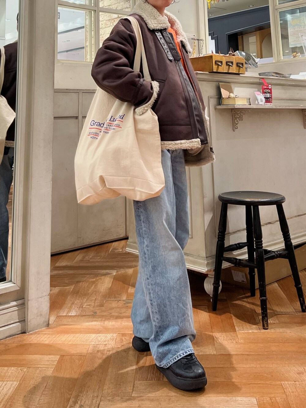 オレンジ系のニット/セーター、ホワイト系のTシャツ/カットソー、ブルー系のデニムパンツを着用したレディースの冬コーディネートの7枚目の写真