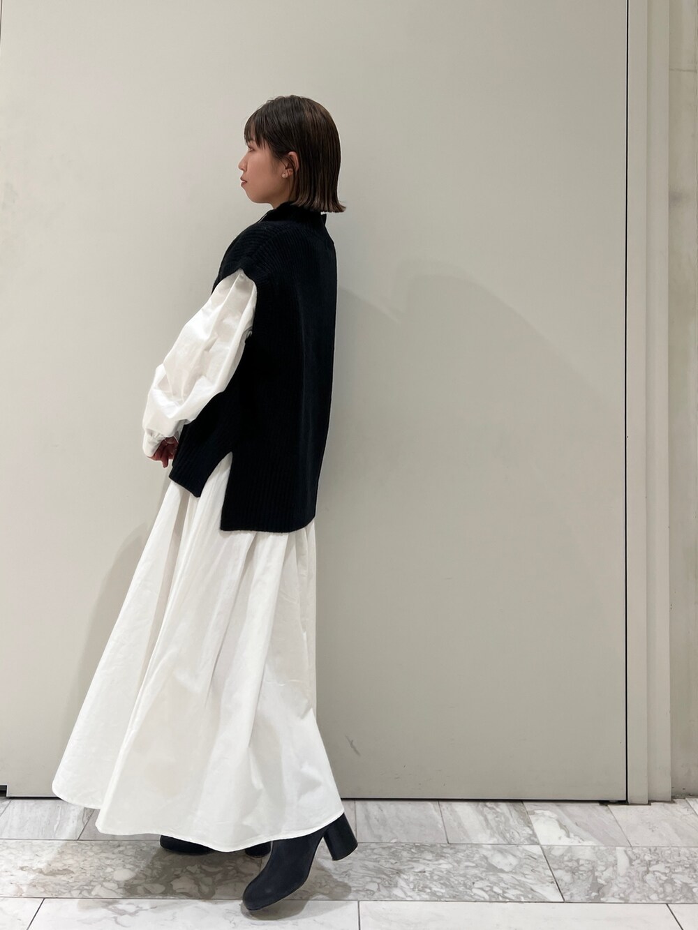 ブラック系のニット/セーター、ブラック系のワンピース、ブラック系のブーツを着用したレディースの冬コーディネートの2枚目の写真