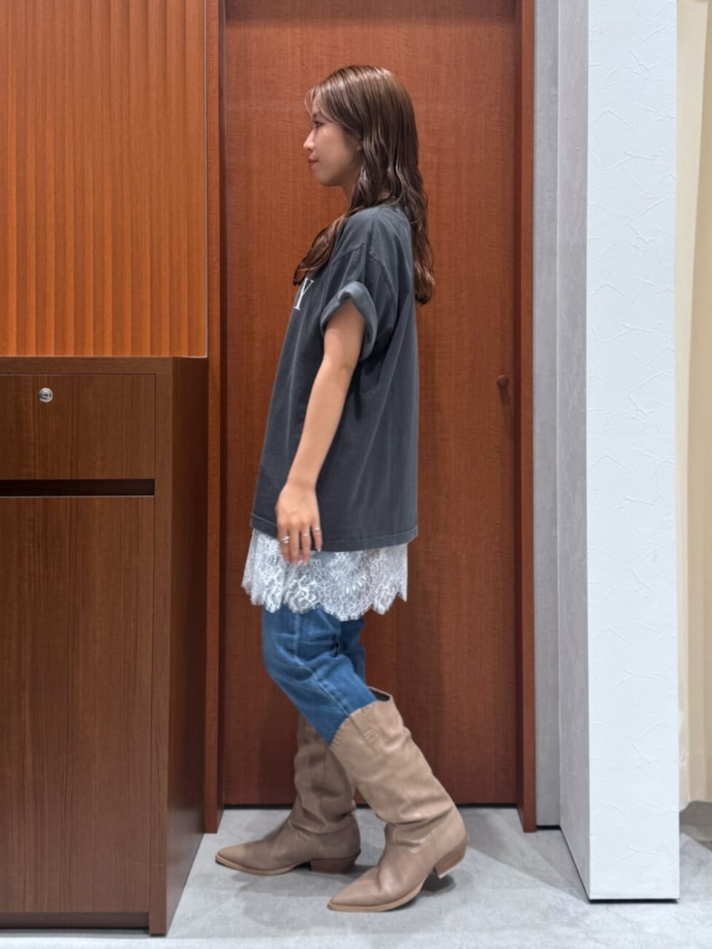 ベージュ系のブーツ、ブルー系のデニムパンツ、ホワイト系のキャミソールを着用したレディースの夏コーディネートの5枚目の写真