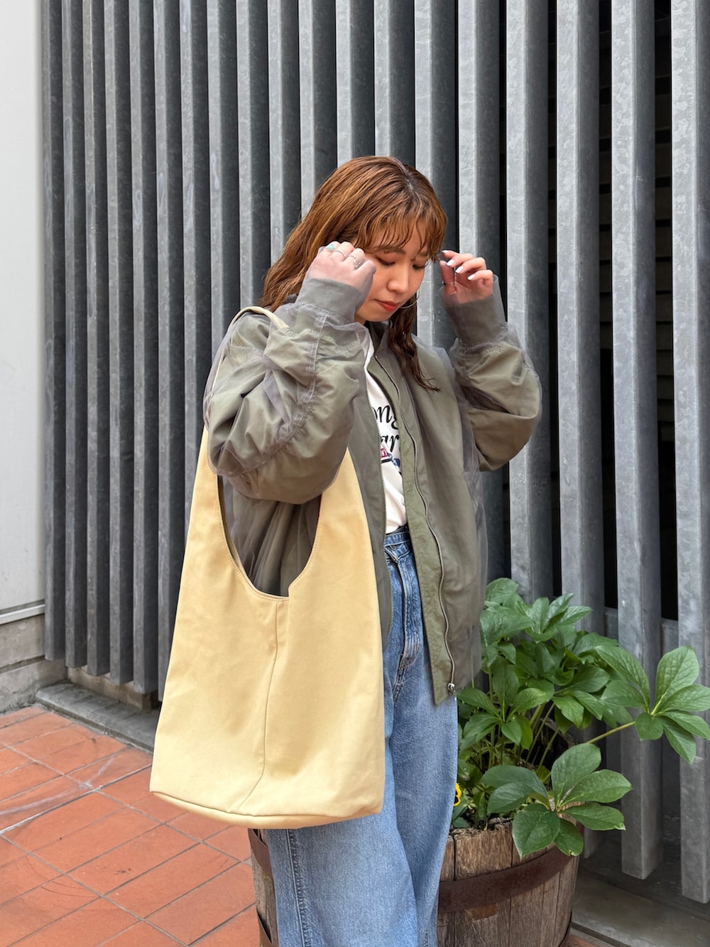 ベージュ系のトートバッグ、ホワイト系のタンクトップ、ブルー系のデニムパンツを着用したレディースの夏コーディネートの6枚目の写真