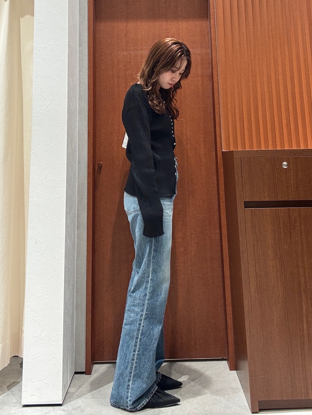 ブルー系のデニムパンツ、ブラック系のカーディガン/ボレロ、ブラック系のパンプスを着用したレディースの春コーディネートの2枚目の写真