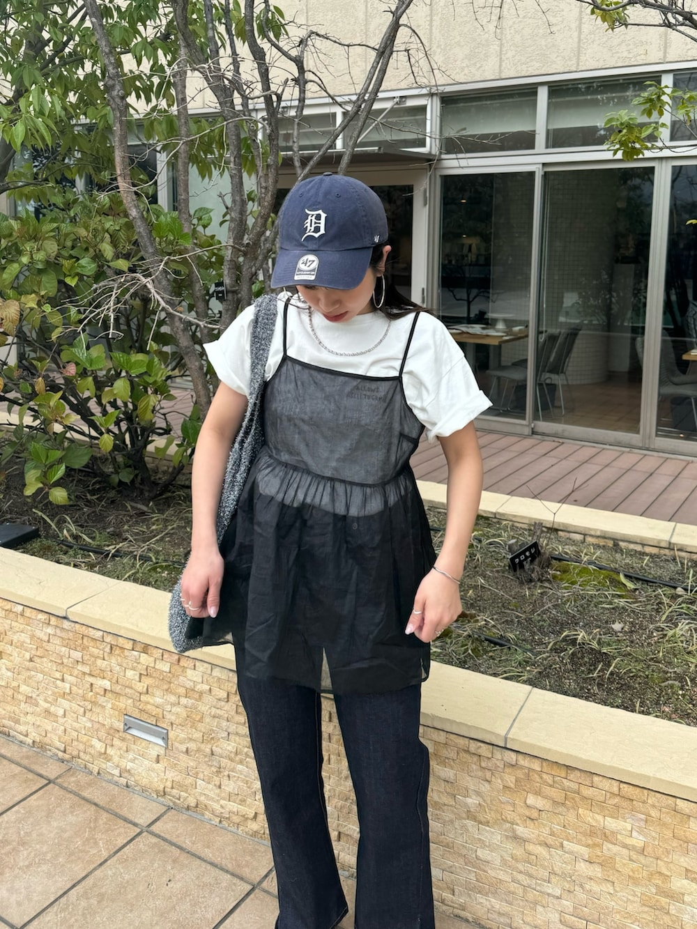 ブルー系のデニムパンツ、ホワイト系のTシャツ/カットソー、ブラック系のキャミソールを着用したレディースの春コーディネートの4枚目の写真