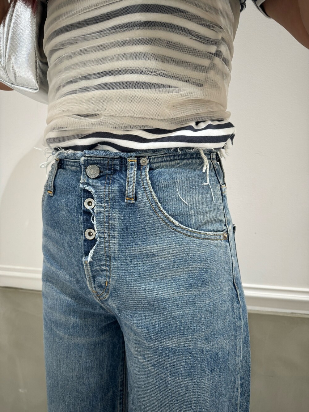 グレー系のTシャツ/カットソー、ベージュ系のキャミソール、ブルー系のデニムパンツを着用したレディースの春コーディネートの6枚目の写真