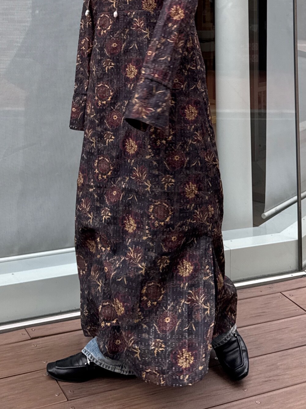 ブラック系のワンピース、ブルー系のデニムパンツ、ブラウン系のネックレスを着用したレディースの冬コーディネートの7枚目の写真