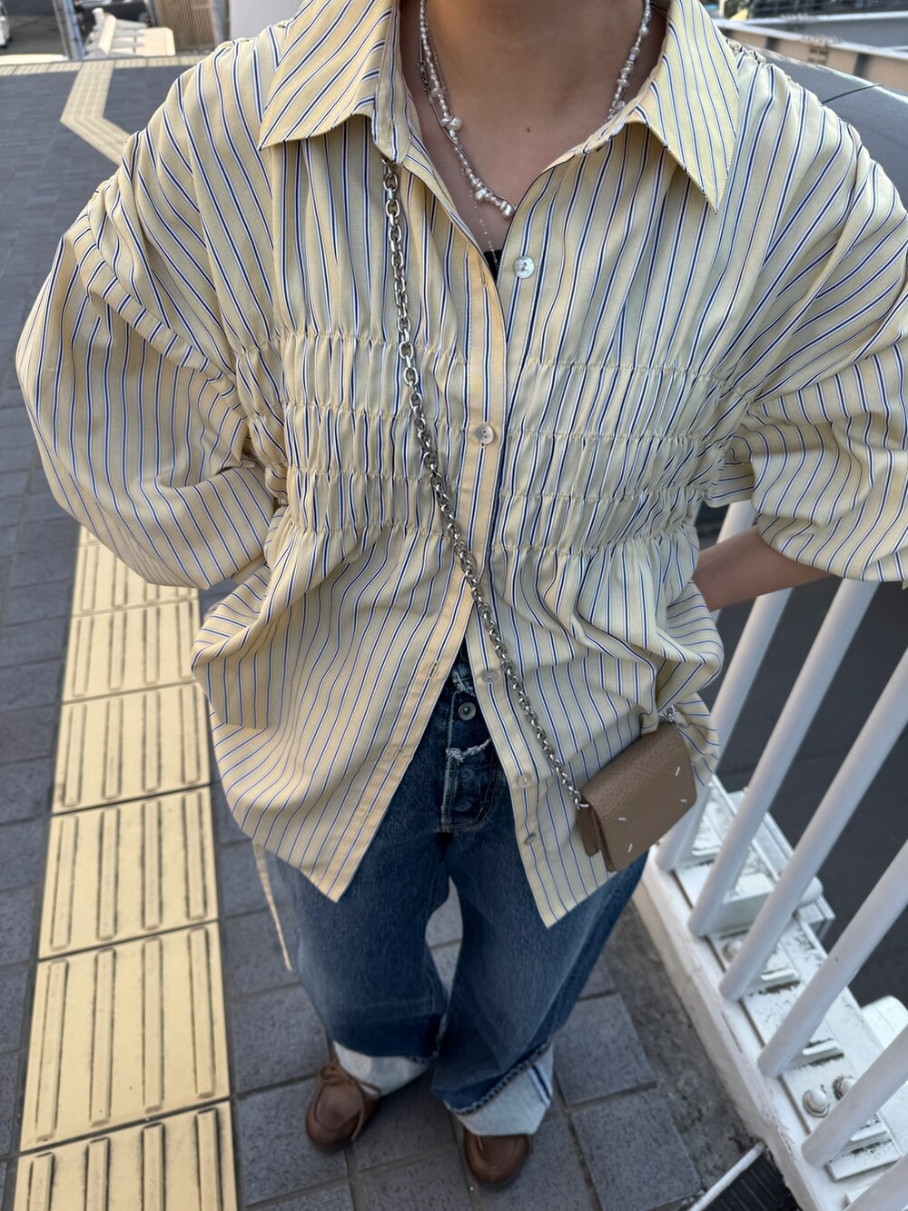 イエロー系のシャツ/ブラウス、ブルー系のデニムパンツ、ブラウン系のローファーを着用したレディースの冬コーディネートの6枚目の写真