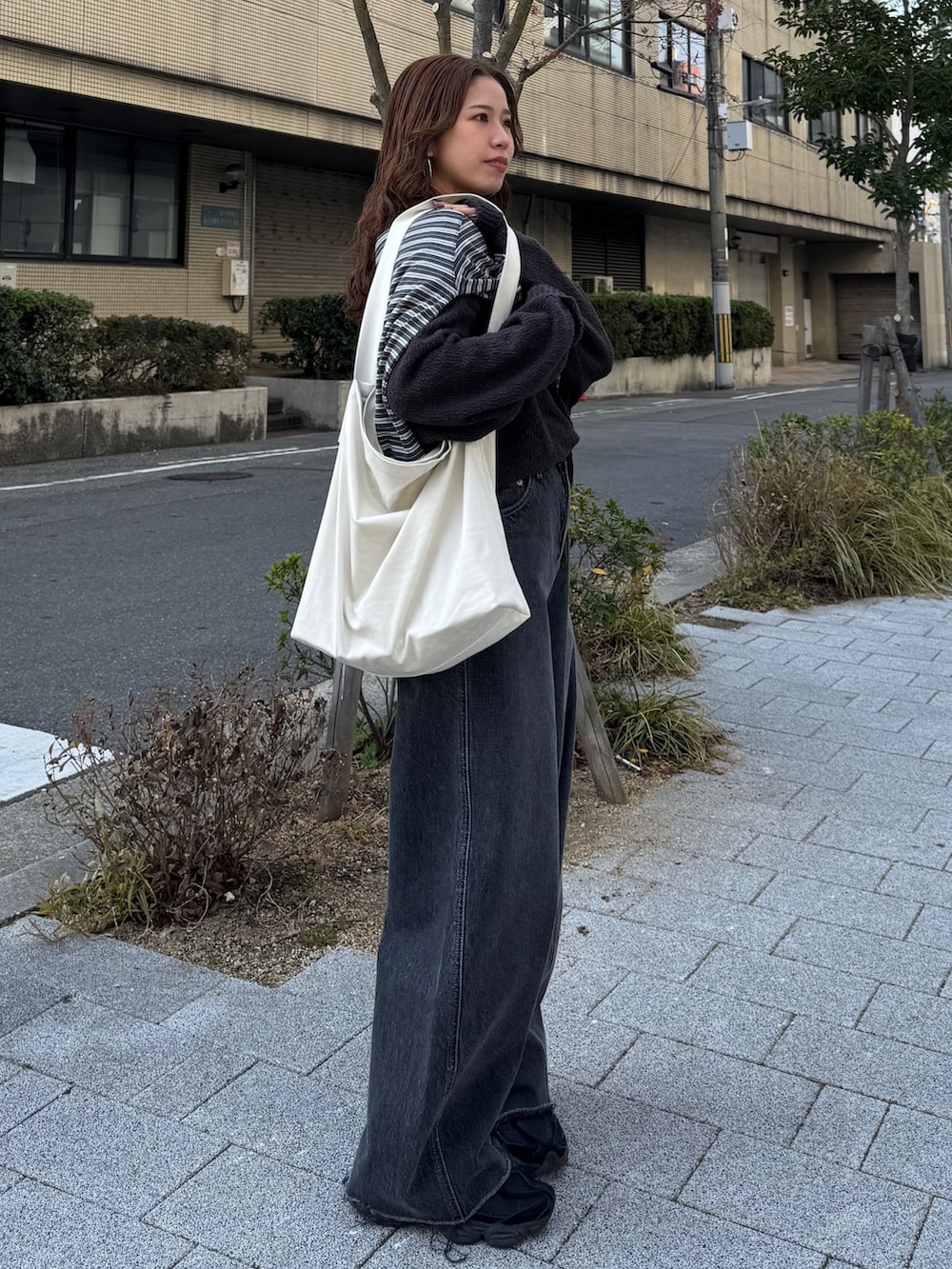 グレー系のニット/セーター、グレー系のTシャツ/カットソー、ブラック系のデニムパンツを着用したレディースの冬コーディネートの3枚目の写真