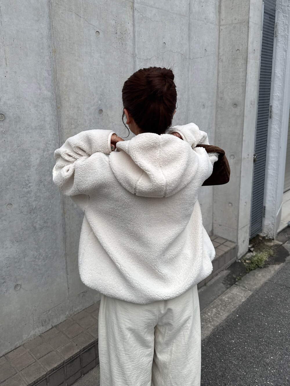 ホワイト系のパーカー、ホワイト系のその他パンツ、ブラウン系のハンドバッグを着用したレディースの秋コーディネートの7枚目の写真