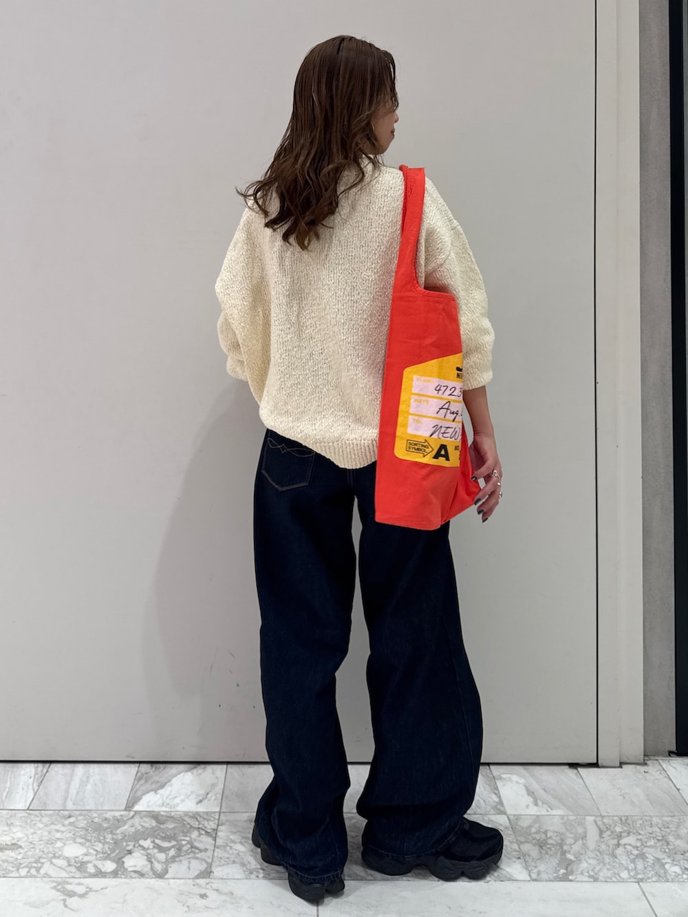 ブルー系のデニムパンツ、ホワイト系のニット/セーター、オレンジ系のトートバッグを着用したレディースの冬コーディネートの6枚目の写真