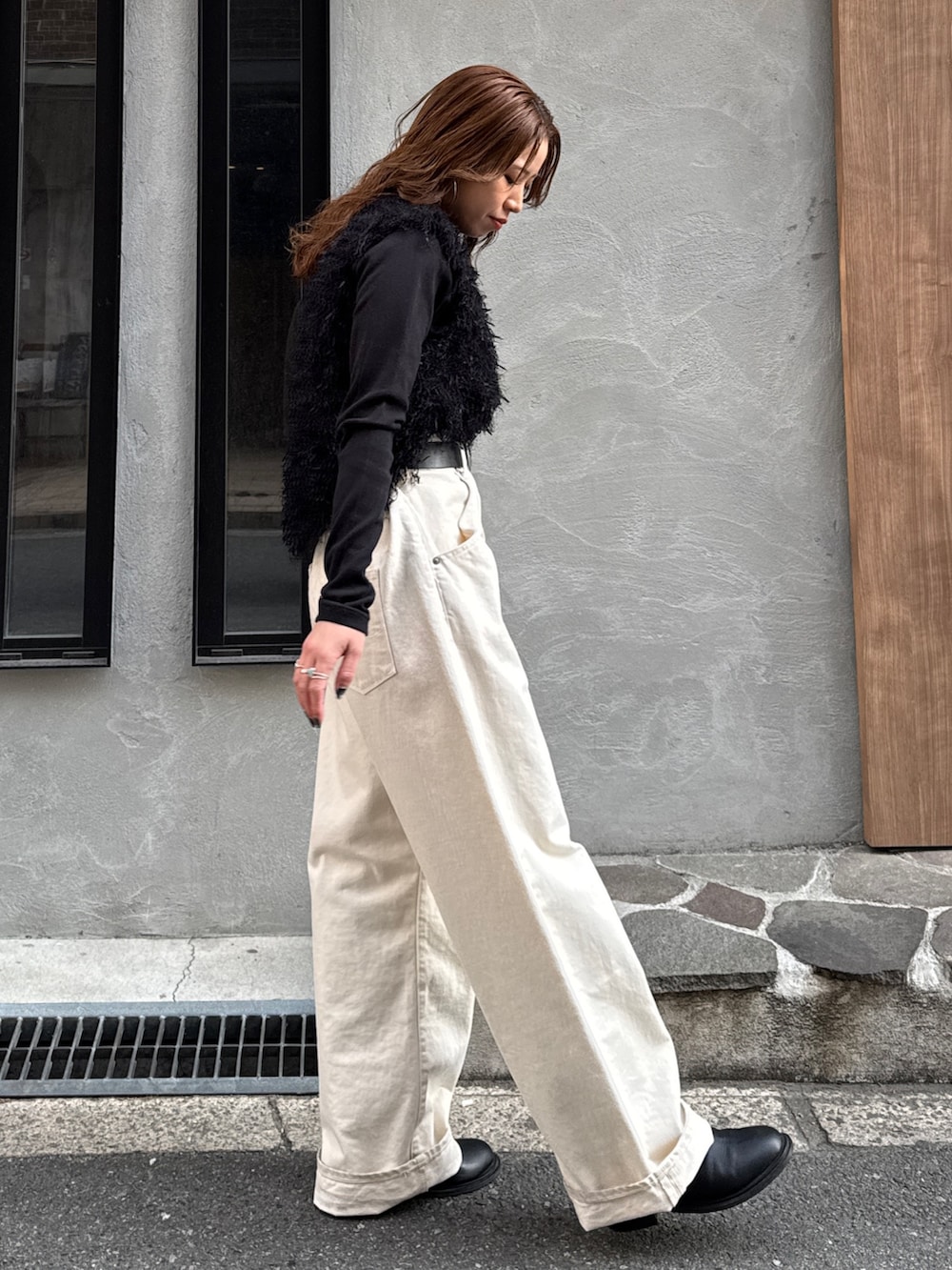 ホワイト系のデニムパンツ、ブラック系のニット/セーター、ブラック系のTシャツ/カットソーを着用したレディースの冬コーディネートの3枚目の写真