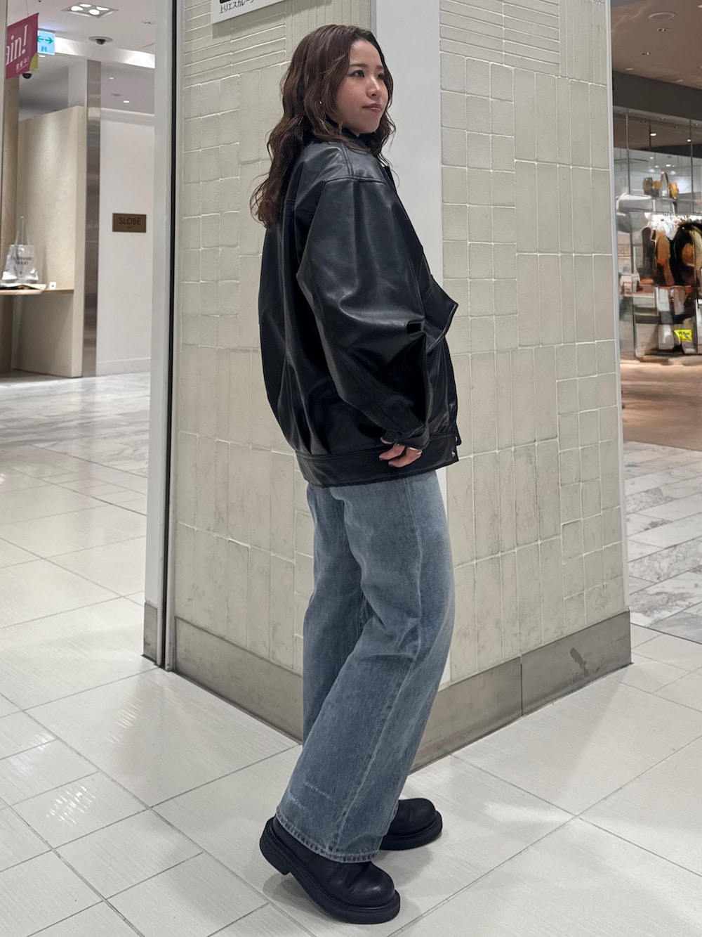 ブルー系のデニムパンツ、ブラック系のブルゾン、イエロー系のニット/セーターを着用したレディースの冬コーディネートの2枚目の写真