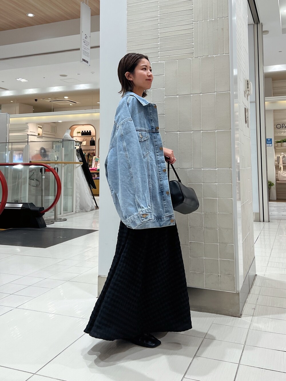 ブラック系のワンピース、グリーン系のタンクトップ、ブルー系のデニムジャケットを着用したレディースの冬コーディネートの3枚目の写真