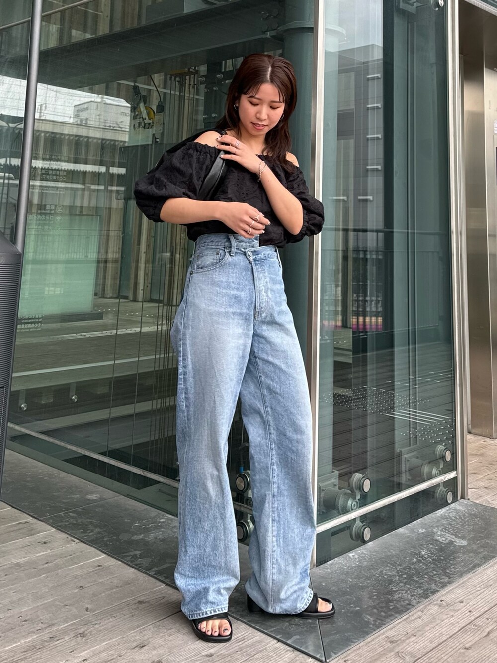 ブルー系のデニムパンツ、ブラック系のシャツ/ブラウス、ブラック系のハンドバッグを着用したレディースの春コーディネートの2枚目の写真