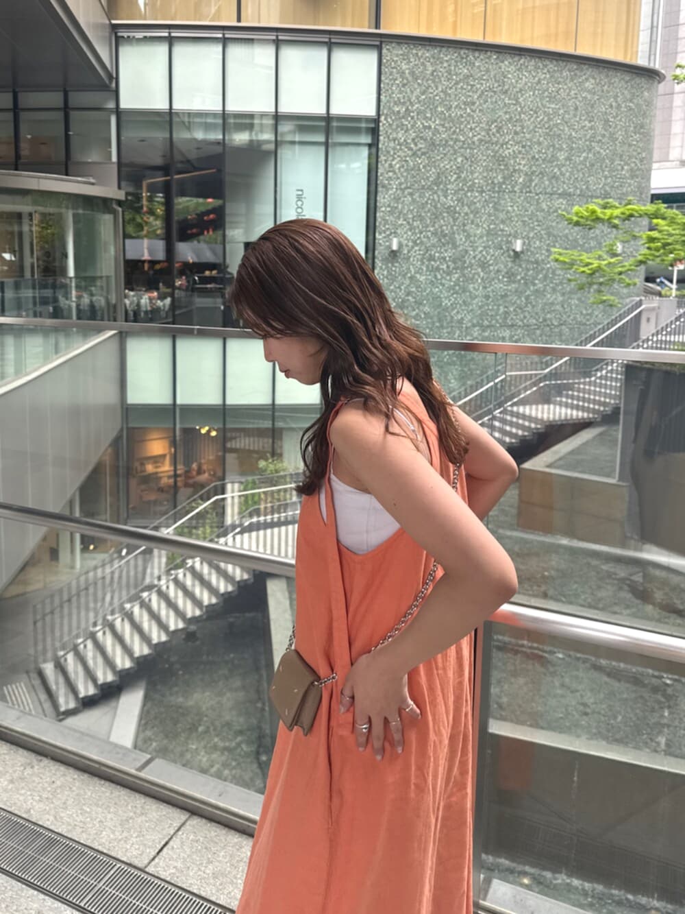 ブルー系のデニムパンツ、オレンジ系のワンピースを着用したレディースの春コーディネートの7枚目の写真