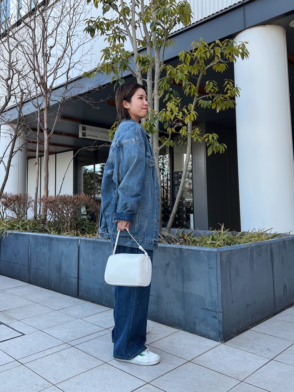 ブルー系のデニムパンツ、ホワイト系のハンドバッグ、ブルー系のデニムジャケットを着用したレディースの冬コーディネートの3枚目の写真