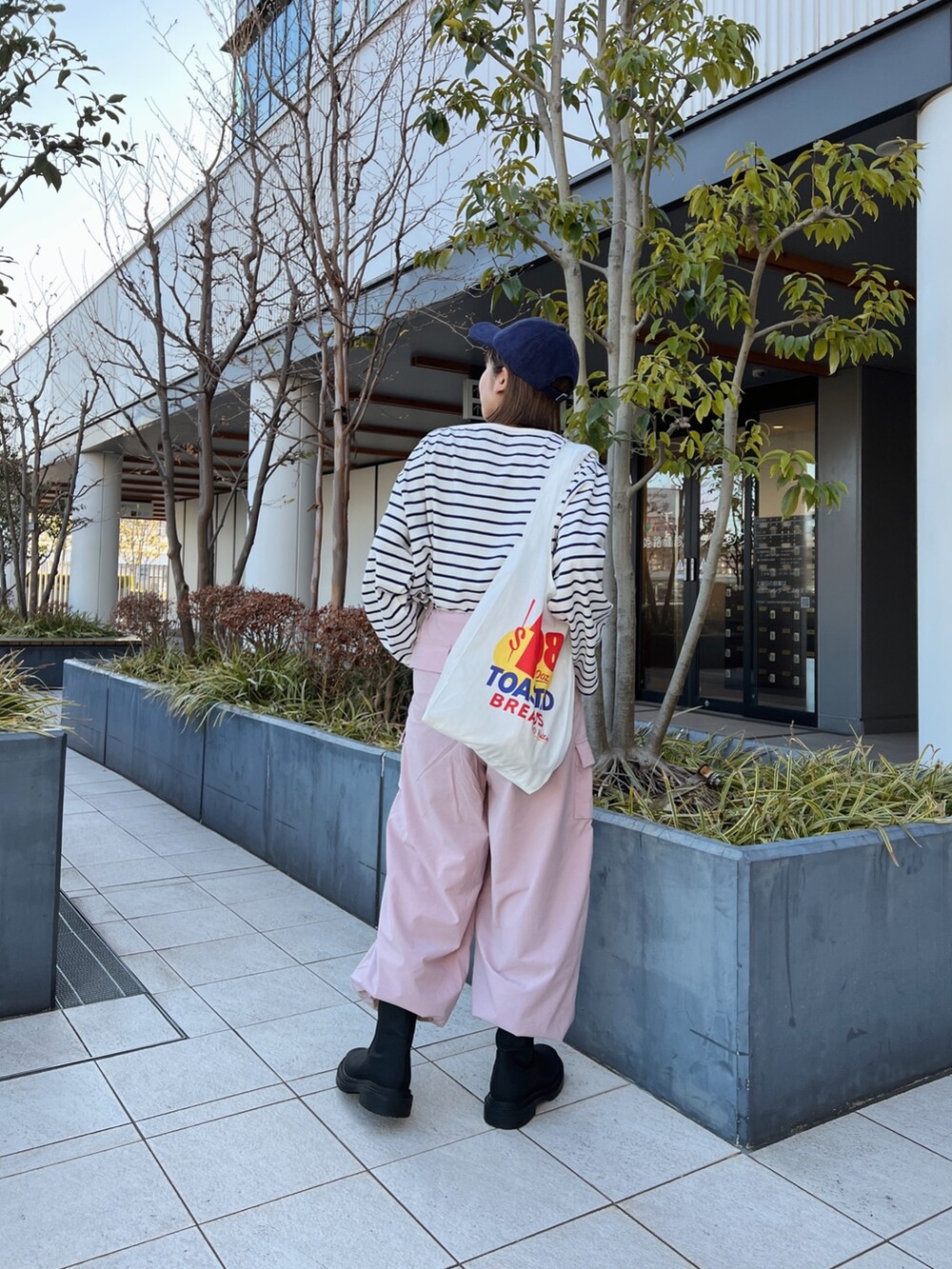 ピンク系のカーゴパンツ、ホワイト系のエコバッグ/サブバッグ、ブルー系のTシャツ/カットソーを着用したレディースの冬コーディネートの6枚目の写真