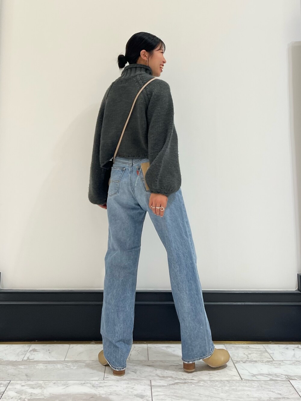 ブルー系のデニムパンツ、グレー系のニット/セーター、ベージュ系のブーツを着用したレディースの秋コーディネートの9枚目の写真