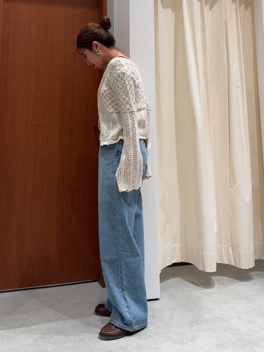 ブルー系のデニムパンツ、オレンジ系のタンクトップ、ホワイト系のカーディガン/ボレロを着用したレディースの春コーディネートの6枚目の写真