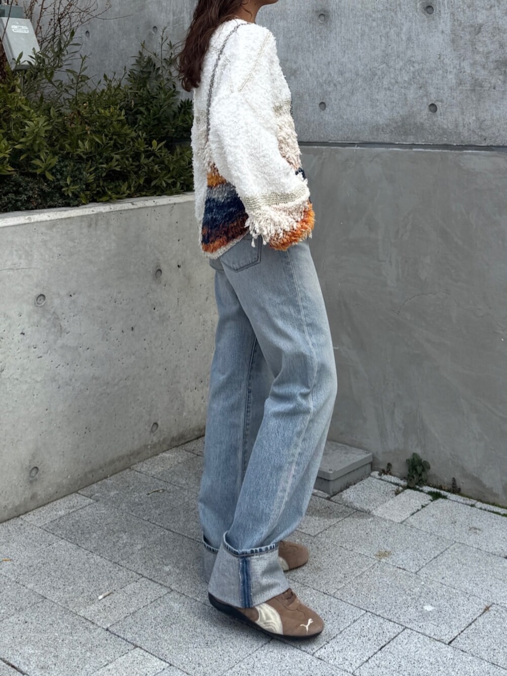 ブルー系のデニムパンツ、ホワイト系のニット/セーター、ブラウン系のスニーカーを着用したレディースの冬コーディネートの3枚目の写真