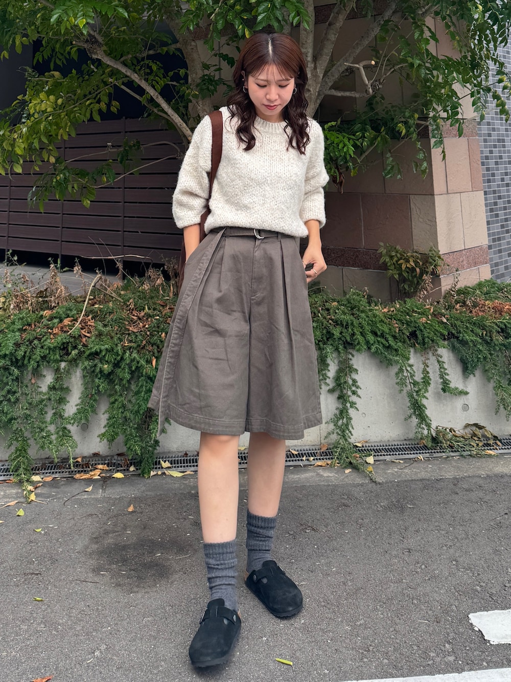 グレー系のチノパンツ、ホワイト系のニット/セーター、ブラウン系のトートバッグを着用したレディースの秋コーディネートの2枚目の写真