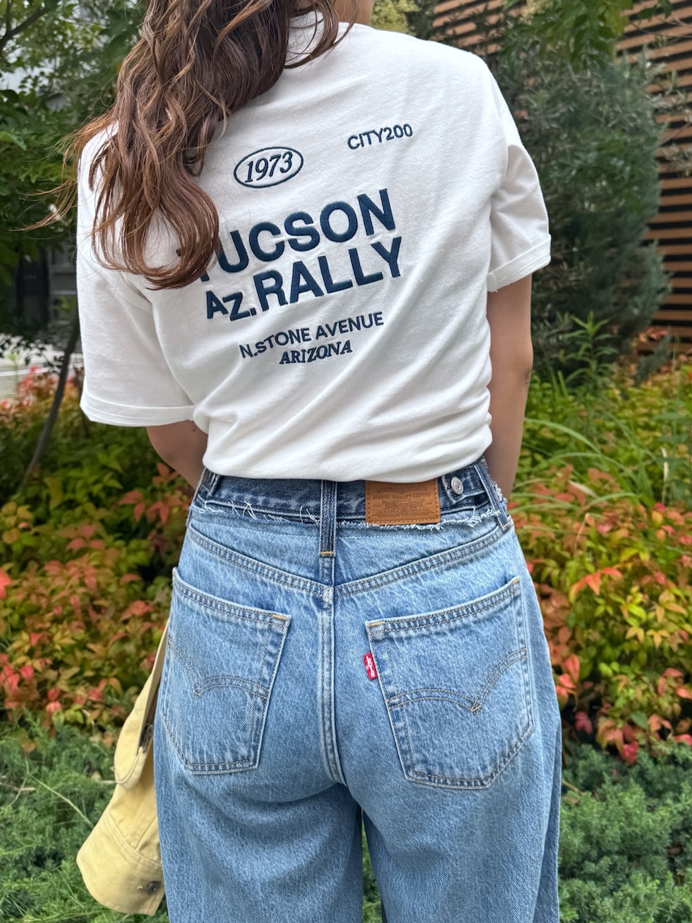 ブルー系のデニムパンツ、イエロー系のブルゾン、ホワイト系のTシャツ/カットソーを着用したレディースの夏コーディネートの9枚目の写真