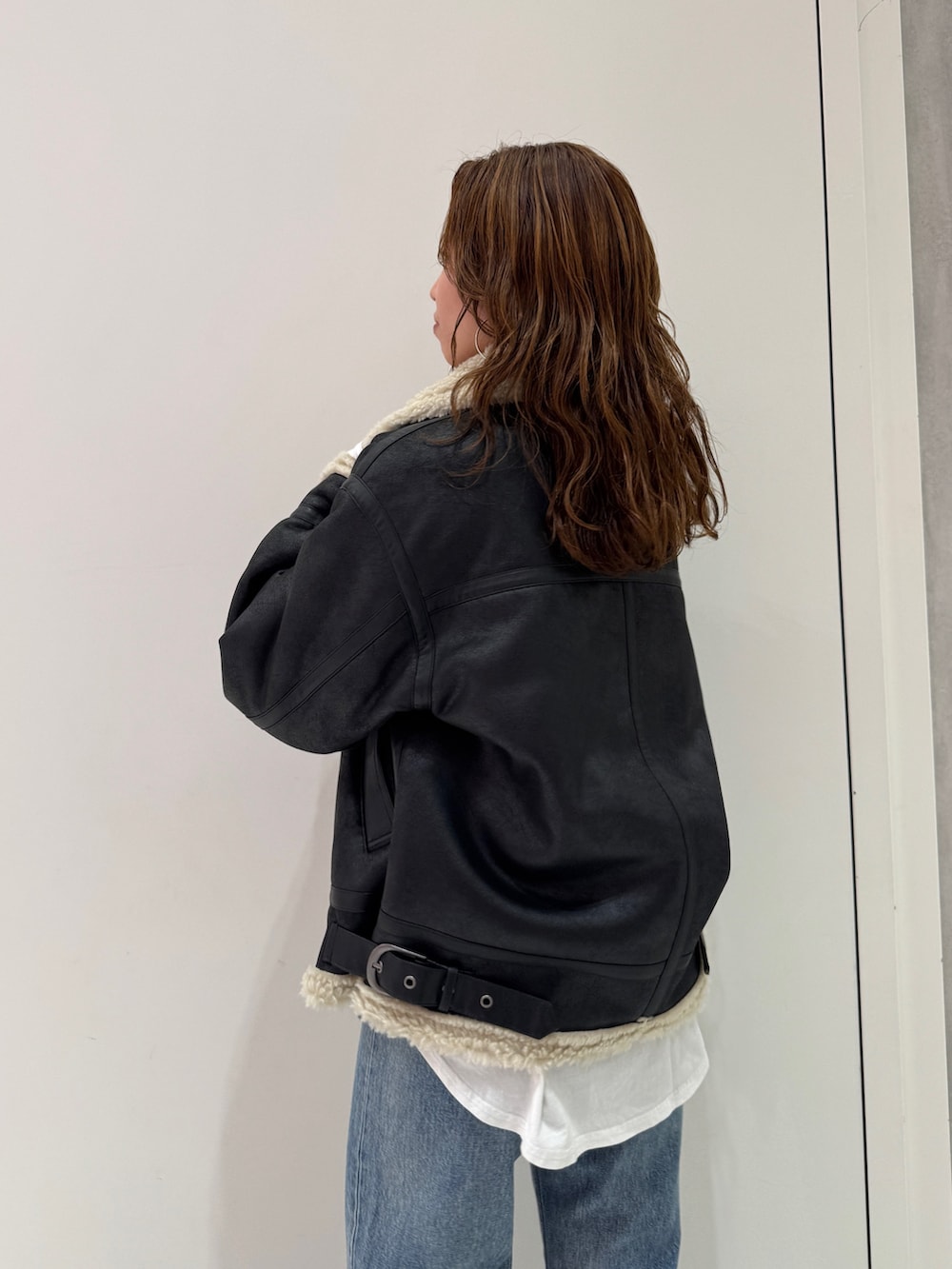 ブラック系のニット/セーター、ホワイト系のTシャツ/カットソー、ブラック系のブーツを着用したレディースの冬コーディネートの9枚目の写真