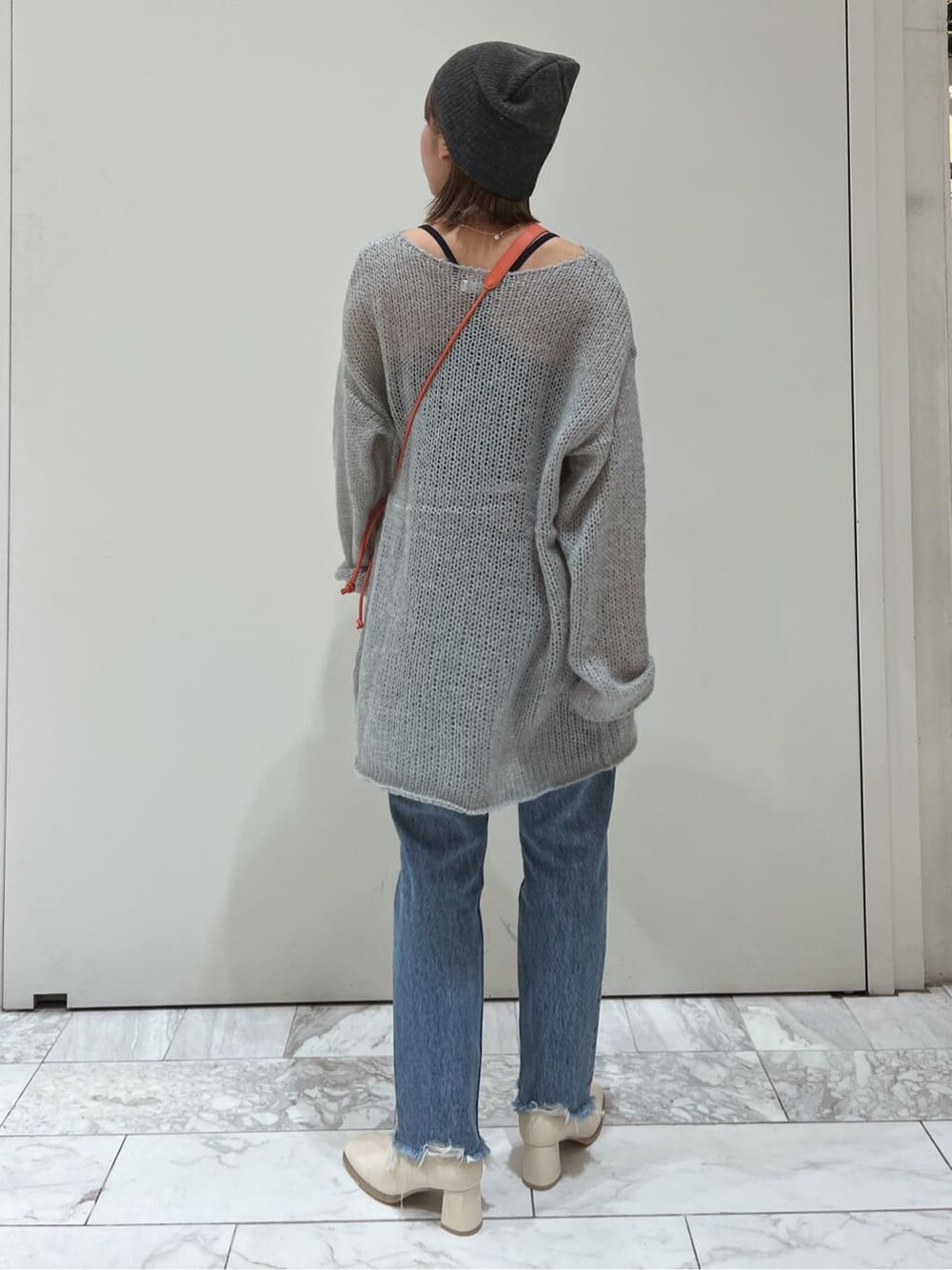 オレンジ系のハンドバッグ、ホワイト系のブーツ、ブルー系のデニムパンツを着用したレディースの秋コーディネートの4枚目の写真