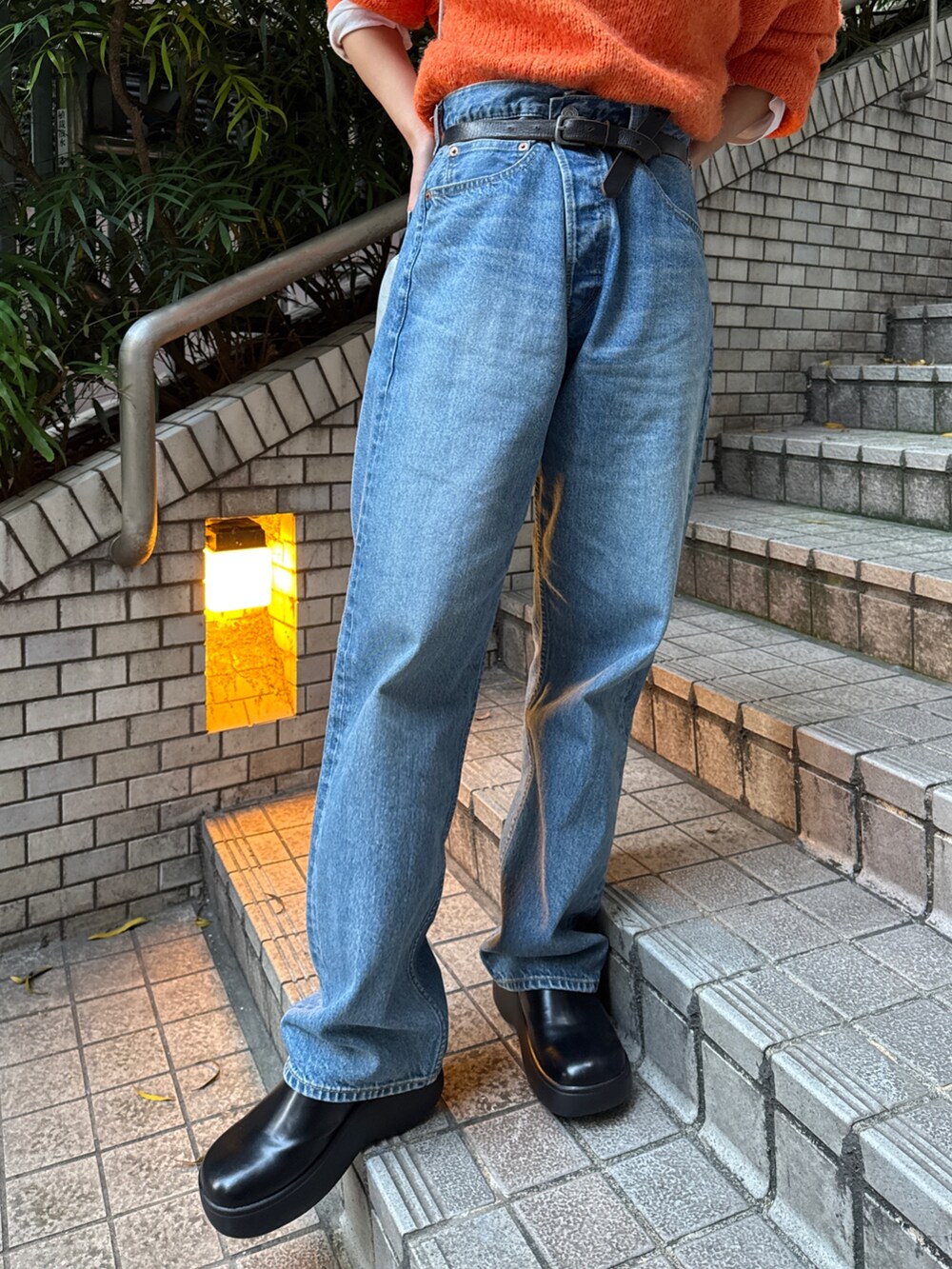 オレンジ系のニット/セーター、ホワイト系のダウンジャケット/コート、ブルー系のデニムパンツを着用したレディースの冬コーディネートの9枚目の写真