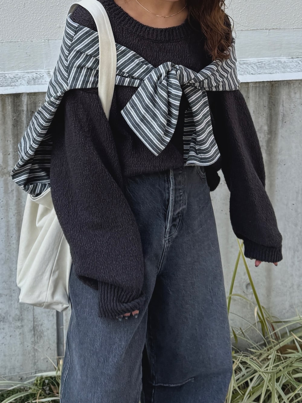 グレー系のニット/セーター、グレー系のTシャツ/カットソー、ブラック系のデニムパンツを着用したレディースの冬コーディネートの7枚目の写真