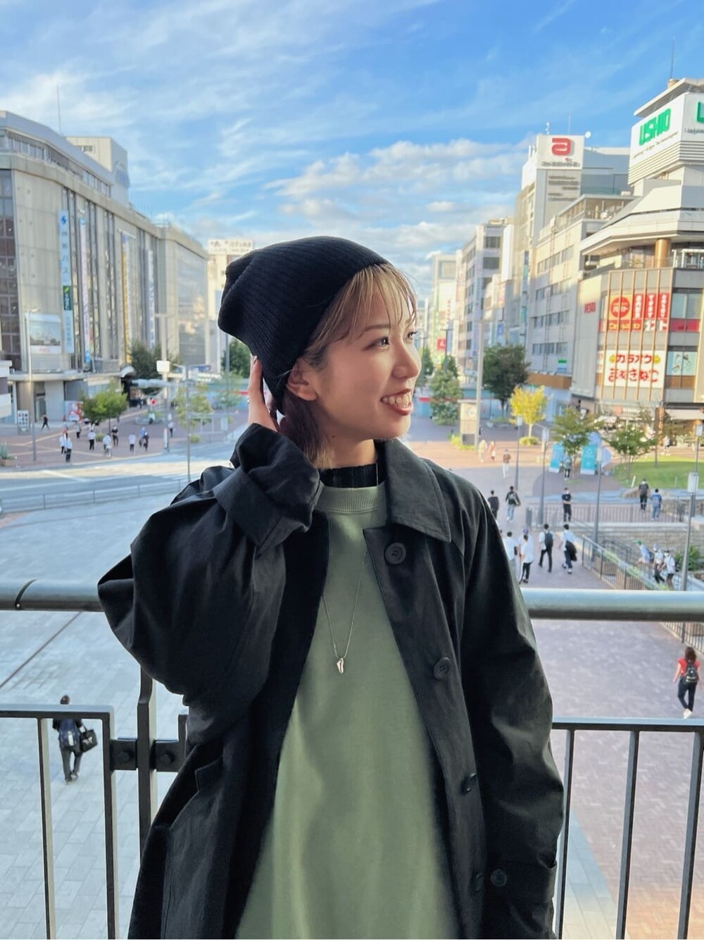 ブラック系のステンカラーコート、グリーン系のワンピース、ブラック系のブーツを着用したレディースの秋コーディネートの7枚目の写真