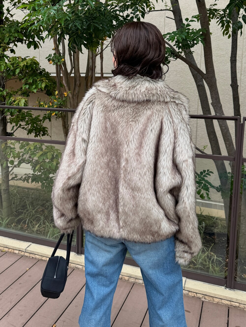 ベージュ系のその他アウター、ブルー系のデニムパンツ、ブラック系のハンドバッグを着用したレディースの秋コーディネートの5枚目の写真