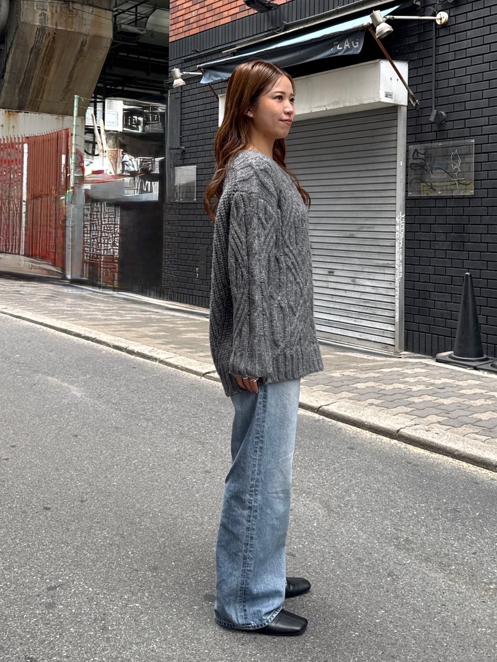 グレー系のニット/セーター、ブルー系のデニムパンツ、ブラック系のサンダルを着用したレディースの秋コーディネートの2枚目の写真