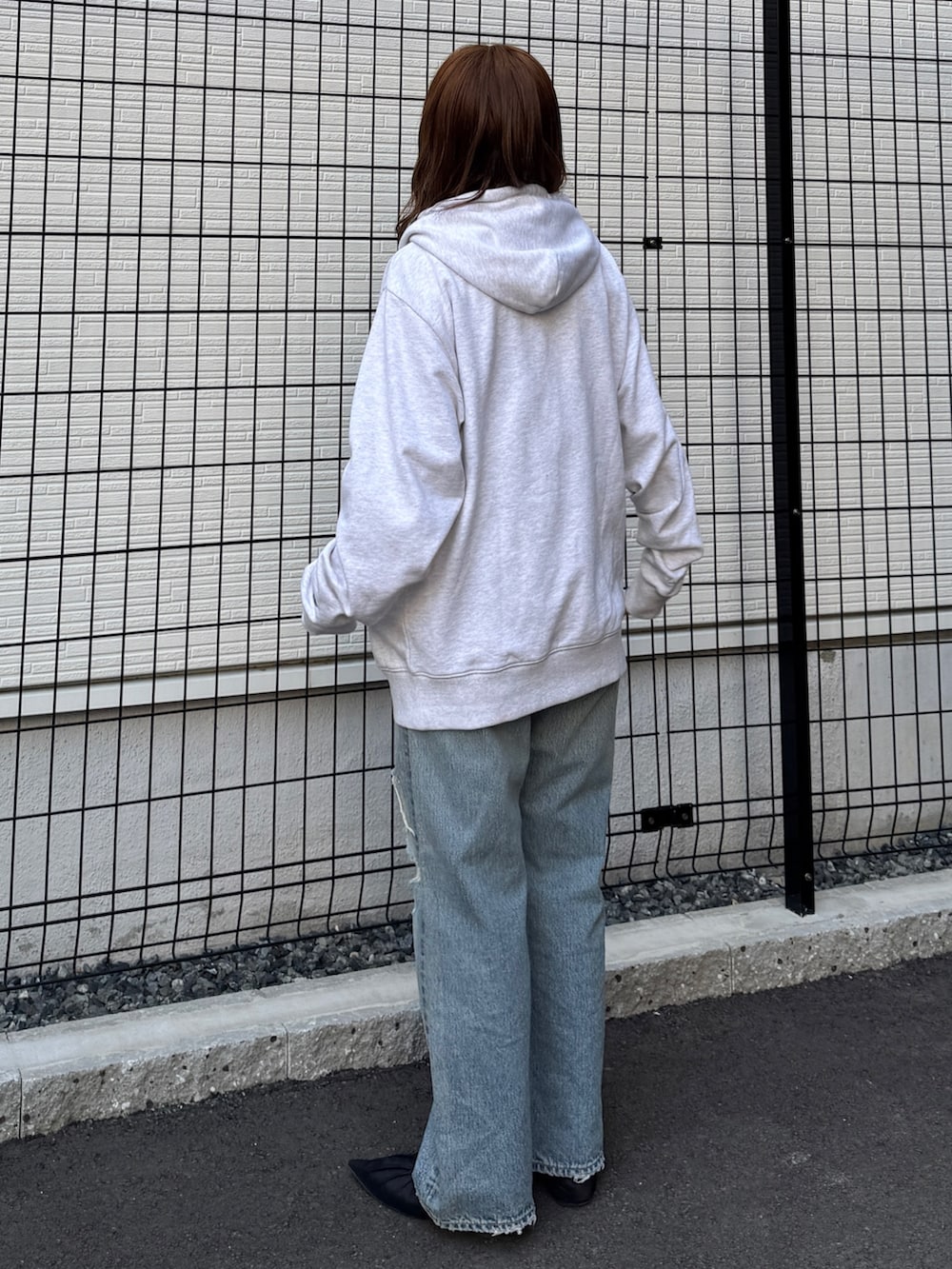 グレー系のパーカー、ブルー系のデニムパンツ、ブラック系のパンプスを着用したレディースの春コーディネートの3枚目の写真