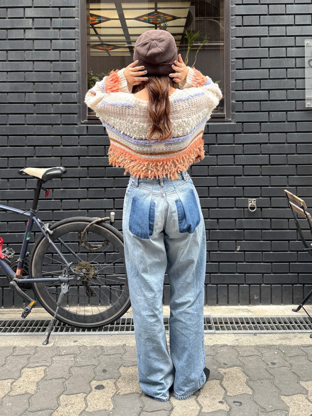 ブルー系のデニムパンツ、ホワイト系のニット/セーター、ブラック系のサンダルを着用したレディースの秋コーディネートの5枚目の写真