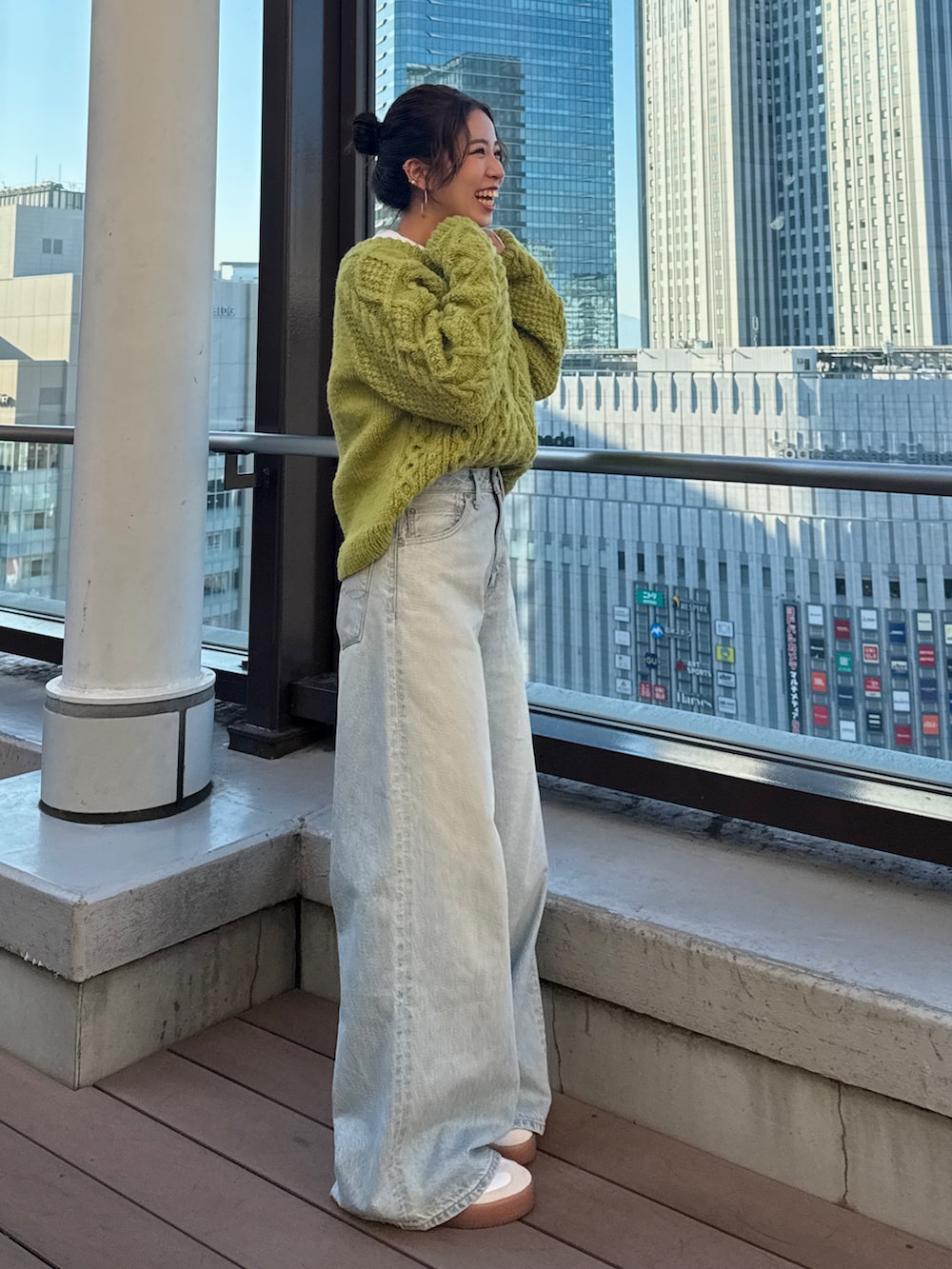 グリーン系のニット/セーター、ホワイト系のTシャツ/カットソー、ブルー系のデニムパンツを着用したレディースの冬コーディネートの7枚目の写真
