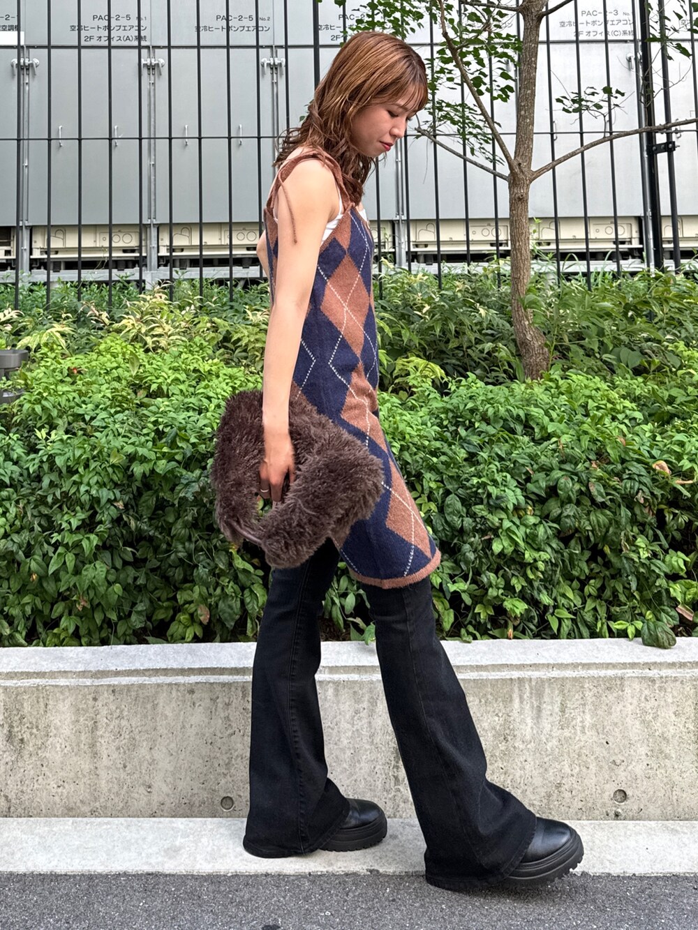 ブラウン系のニット/セーター、ブラック系のデニムパンツ、ブラウン系のハンドバッグを着用したレディースの夏コーディネートの4枚目の写真