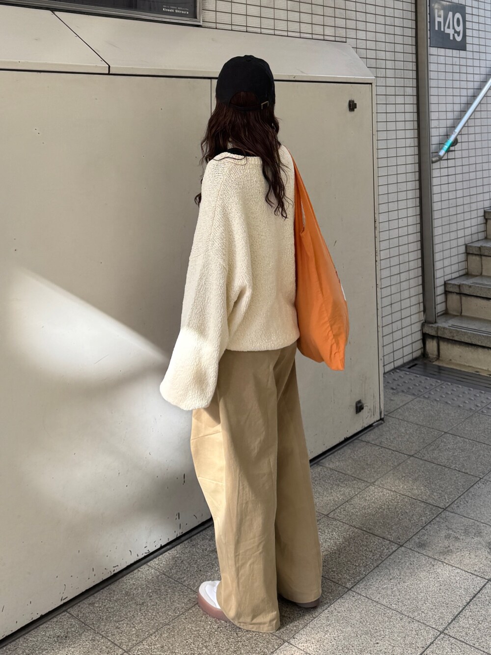 ベージュ系のチノパンツ、ホワイト系のニット/セーター、オレンジ系のエコバッグ/サブバッグを着用したレディースの冬コーディネートの9枚目の写真