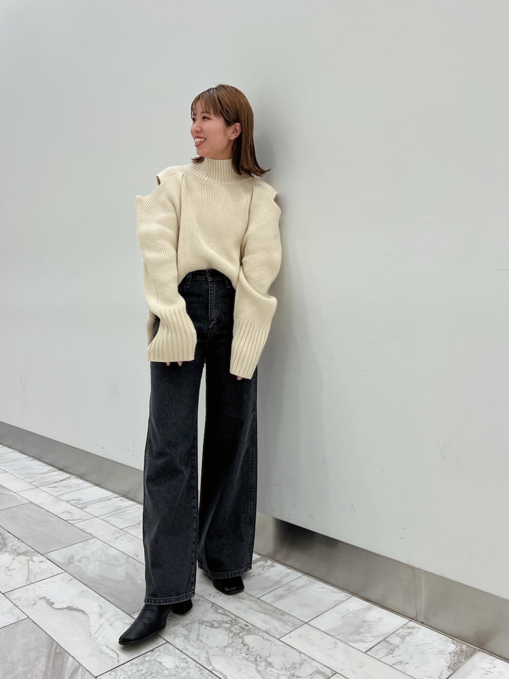 ブラック系のデニムジャケット、ホワイト系のニット/セーター、ブラック系のデニムパンツを着用したレディースの秋コーディネートの5枚目の写真