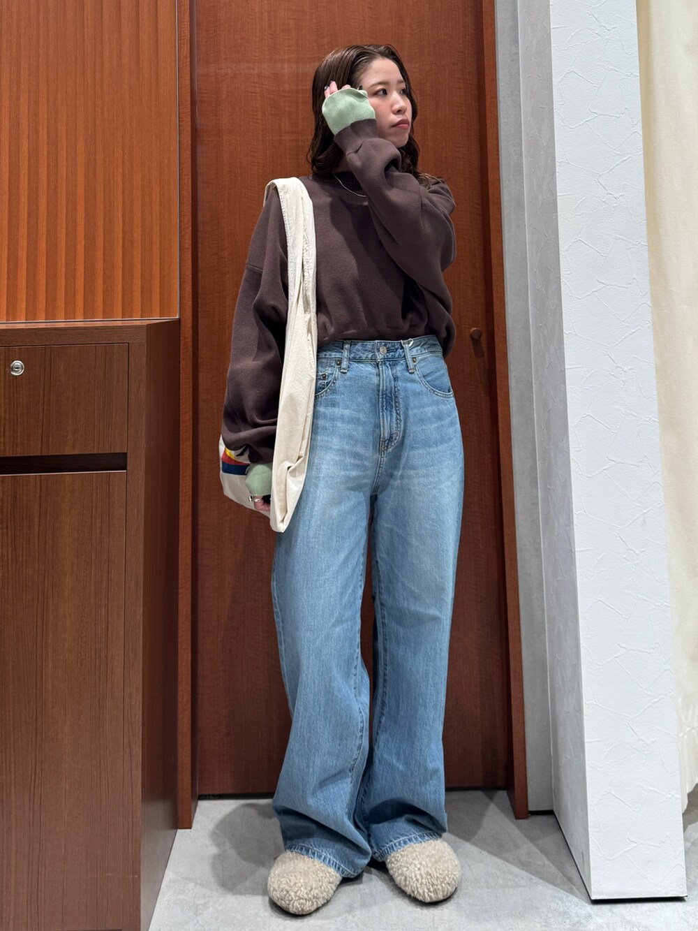 ブルー系のデニムパンツ、ブラウン系のニット/セーター、ホワイト系のトートバッグを着用したレディースの冬コーディネートの6枚目の写真