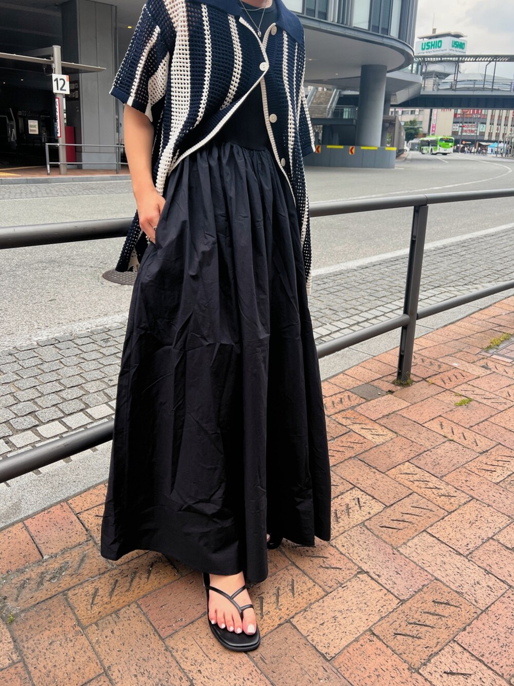 ブラック系のワンピース、ブルー系のカーディガン/ボレロ、ブラック系のサンダルを着用したレディースの春コーディネートの6枚目の写真