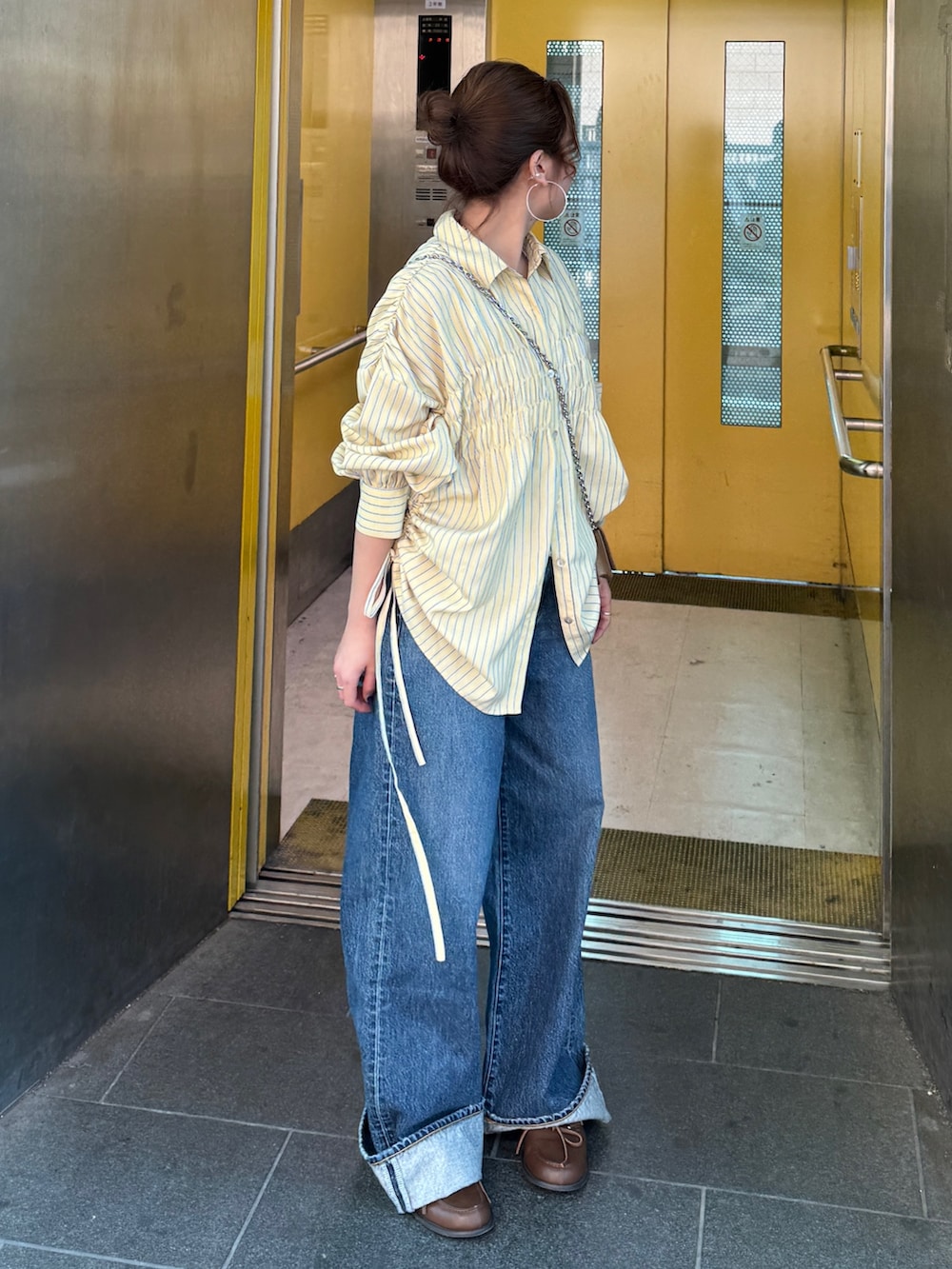 イエロー系のシャツ/ブラウス、ブルー系のデニムパンツ、ブラウン系のローファーを着用したレディースの冬コーディネートの10枚目の写真