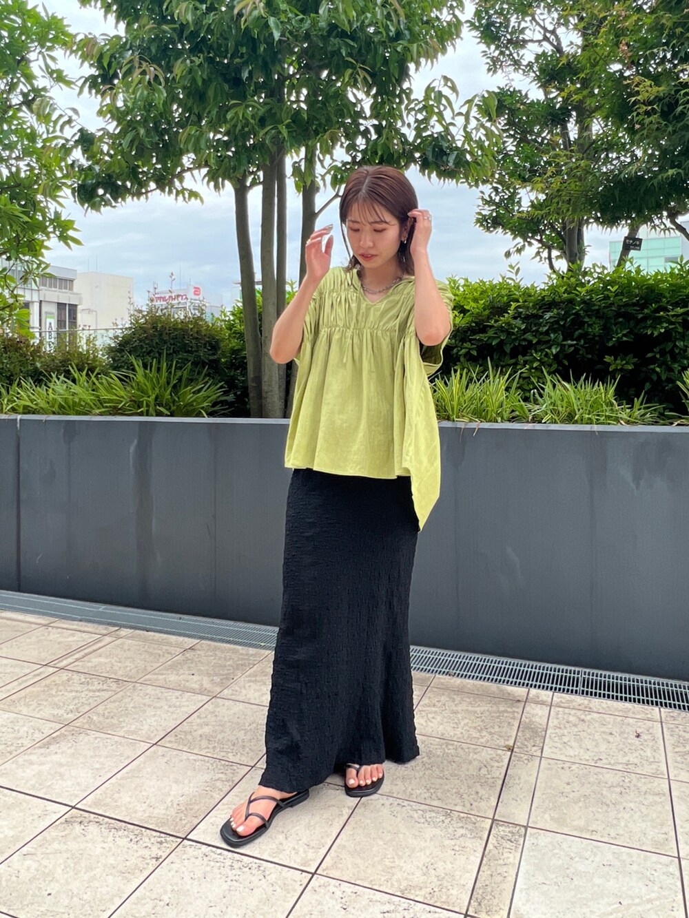 グリーン系のシャツ/ブラウス、ブラック系のスカート、ブラック系のサンダルを着用したレディースの夏コーディネートの3枚目の写真