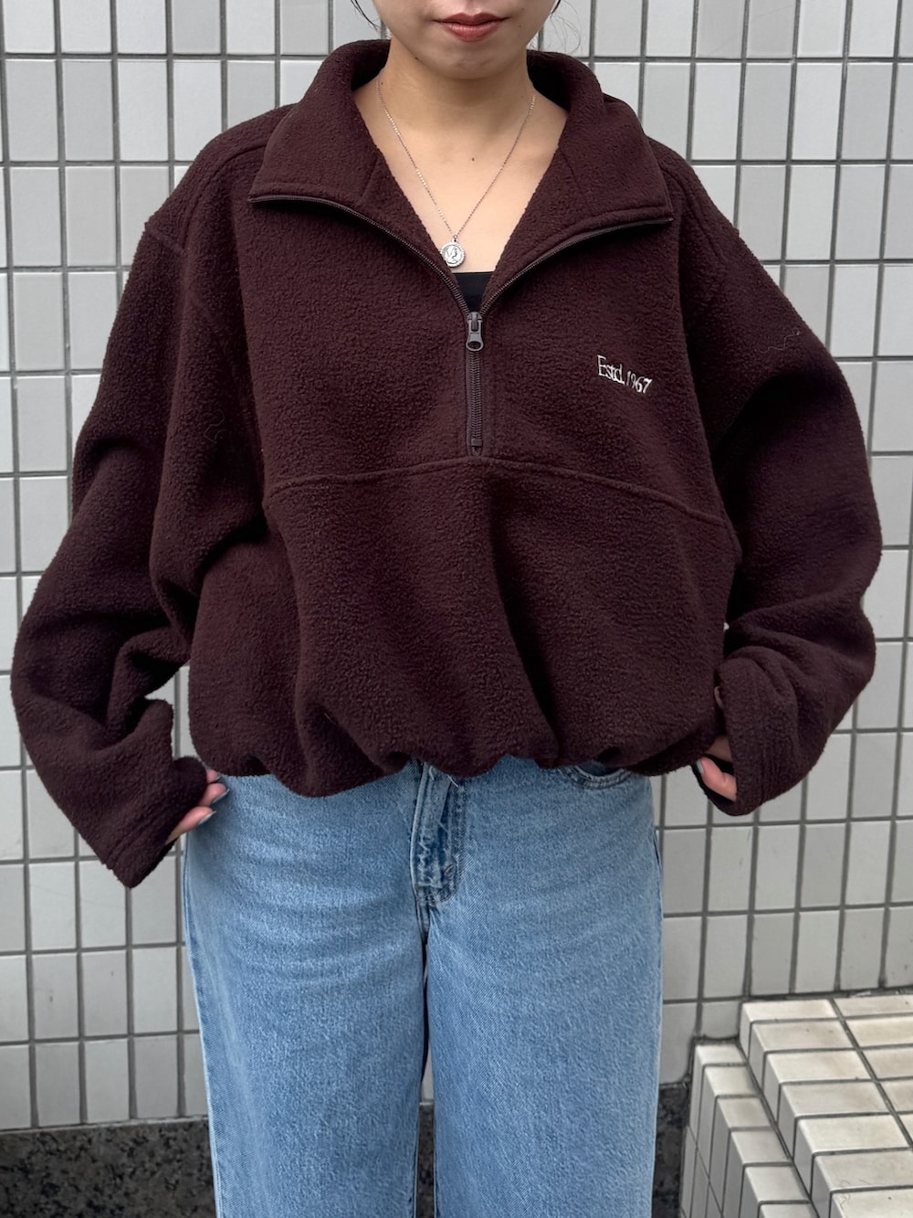 ブラウン系のパーカー、ブルー系のデニムパンツ、ブラック系のサンダルを着用したレディースの秋コーディネートの7枚目の写真